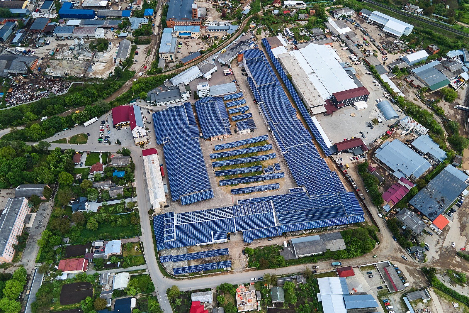 Aerial view of a cluster of commercial buildings with blue solar panels on the roofs.